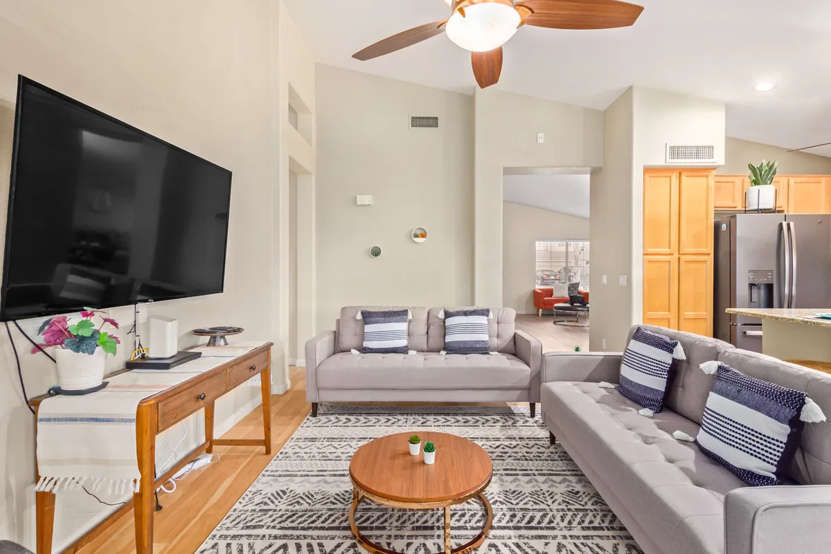 A living room featuring a large flat-screen TV, multiple sofas, a coffee table, and a decorative rug, creating an inviting space for families to relax, watch movies, or entertain guests.