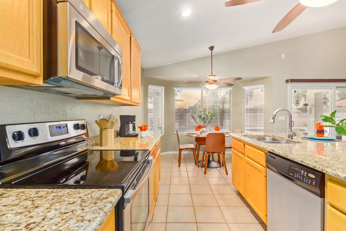 A kitchen and dining area bathed in natural light, featuring a kitchen island, a dining table, and large windows. The clean, cozy aesthetic creates an ideal atmosphere for both casual breakfasts and lively group gatherings.