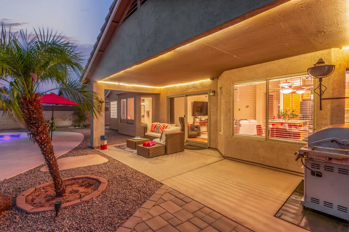 An outdoor seating area adjacent to a pool, accented by a palm tree and warm outdoor lighting. The setting invites both relaxation and entertaining, blending natural surroundings with comfortable amenities.