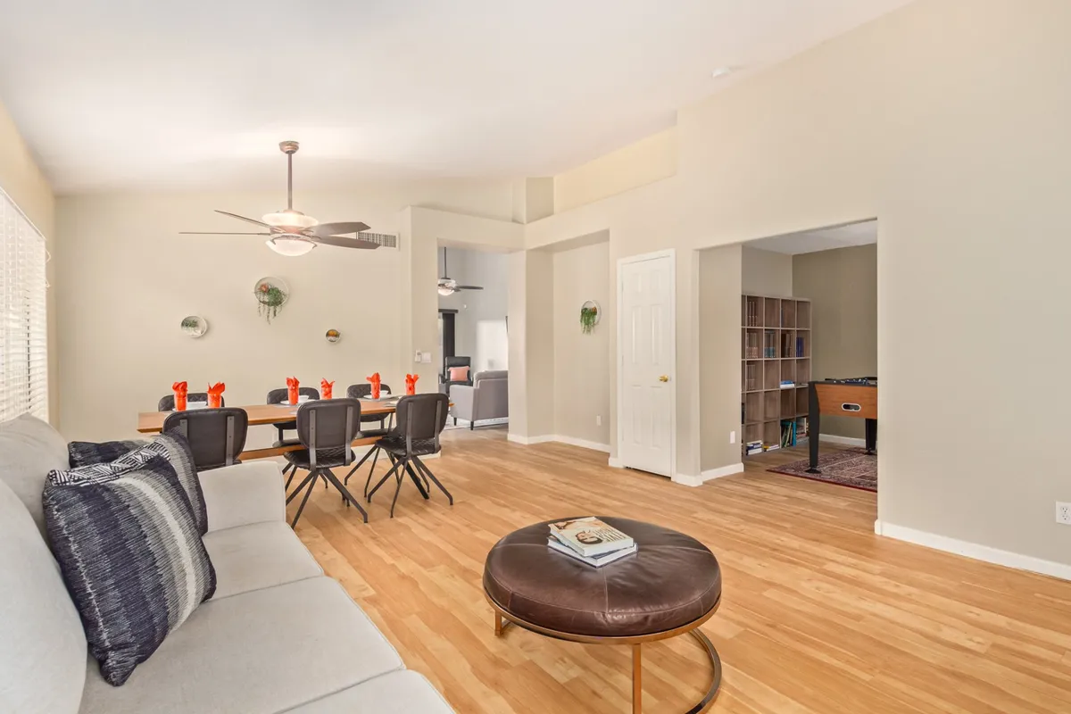 A cozy scene with a dining table and chairs adjacent to a comfortable sofa, complemented by a round coffee table and wall sconces, creating a casual and welcoming ambiance for group activities.